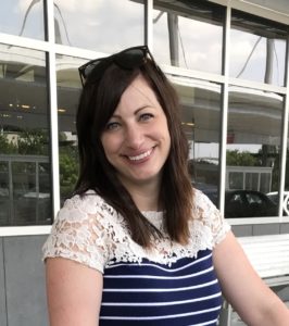 Dr. Kelly Oten smiling and wearing a short-sleeve blue and white striped shirt