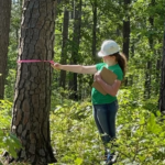 4-H youth using a Biltmore stick to measure a tree for the Spring 2022 4-H Forestry contest.