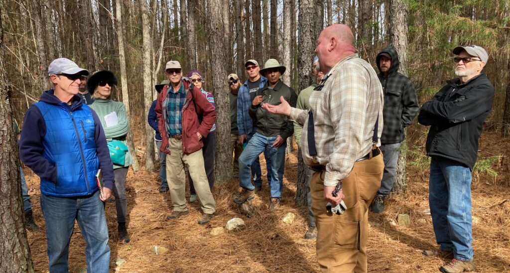 A man teaches a group in a forest.