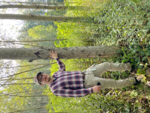 Image of Dr. Will Kohlway standing next to a poplar tree in a forest.