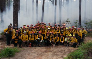 Group photo of Fire Week participants in front of a prescribed burn at North Carolina State Parks.