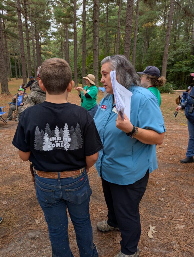 An adult and a 4-H youth member in a stand of trees talking